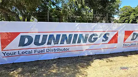 Banner attached to a wire fence shows the excellent blockout characteristics of 12×12 banner mesh, helping builders maintain privacy, site presentation, and professional street-facing appearance throughout construction.