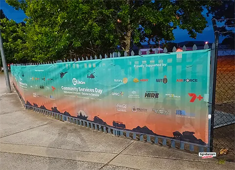 Shows an image late sunset of a banner sign fitted to a picket fence