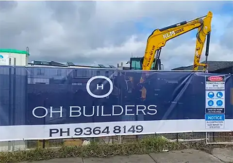 Customer supplied photo showing a continuous branded band along a 50 metre mesh banner roll, with logo and vertical safety signage printed for an industrial supplies reseller.