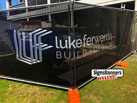 Image shows the mesh site wrap banner installed (corner view) black with silver logo. The customer purchased this mesh direct from Signs Banners Online