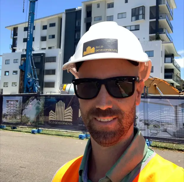A builder casually standing infront a row of fence signage.