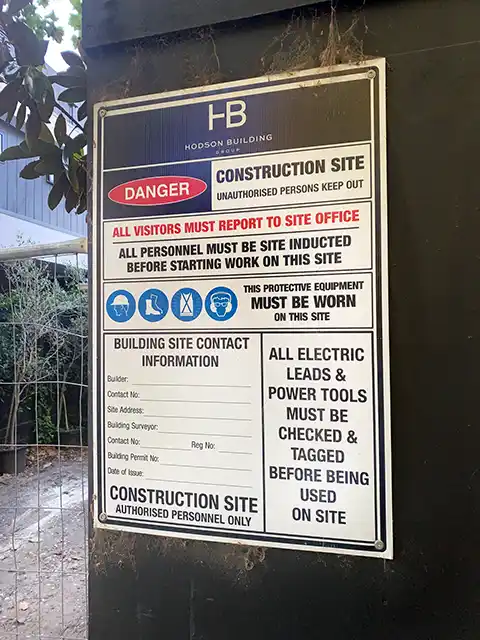 A Tradie casually standing infront of the sign.