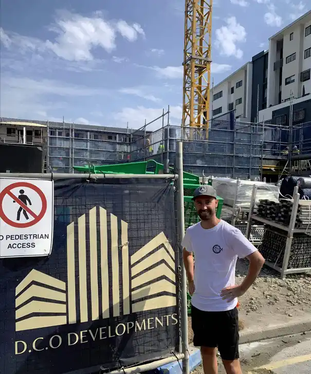 A Tradie casually standing infront of the sign.