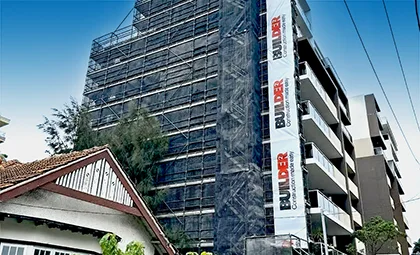 Shows a large building covered with mesh and a large vertical hanging mesh banner sign.