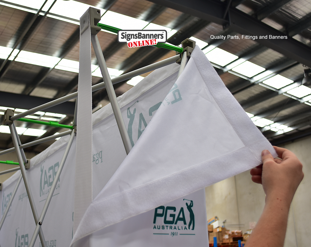 Close-up of a pop-up display frame with hook-and-loop edges and printed PGA Australia fabric panel being fitted by hand.